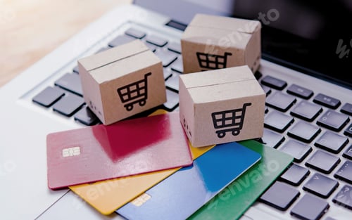 Preview: Shopping online. Credit card and cardboard box with a shopping cart logo on laptop keyboard.