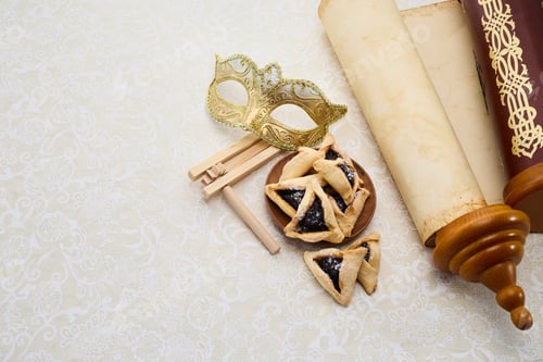 Preview: Purim Celebrations. Golden mask, scroll, gragger, and hamantaschen on decorative background