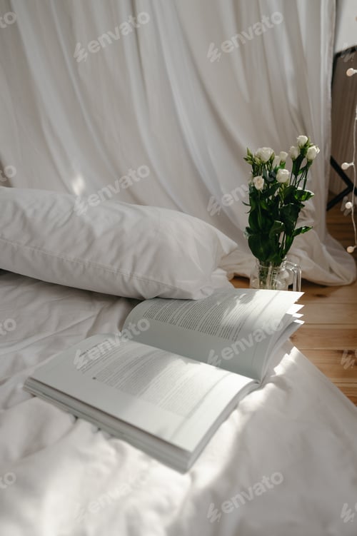 Preview: Bed with white sheets, magazine, flowers. Interior details. morning vibe, copy space, light