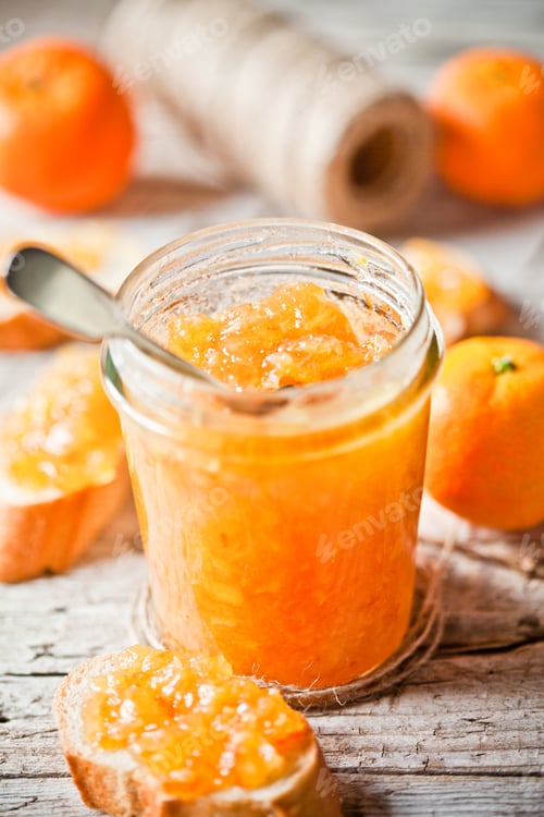 Preview: orange jam in glass jar, tangerines and bread