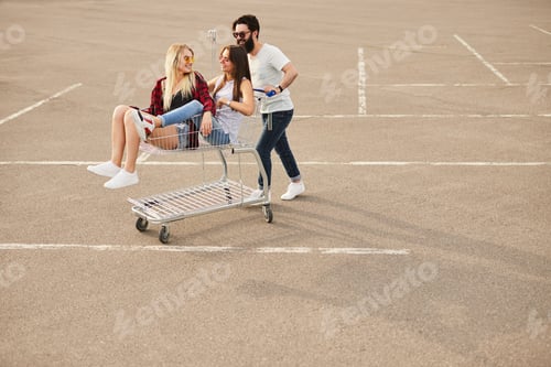 Preview: Man pushing cart with girlfriends on parking lot