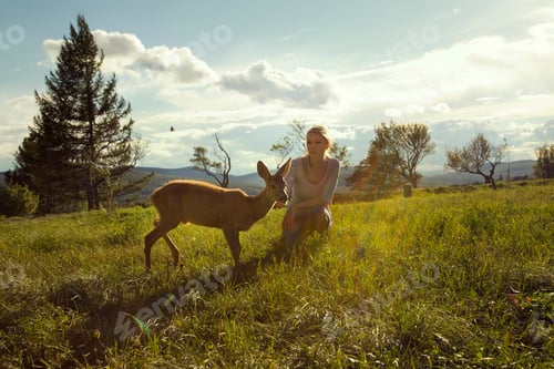 Preview: Young woman in field with fawn