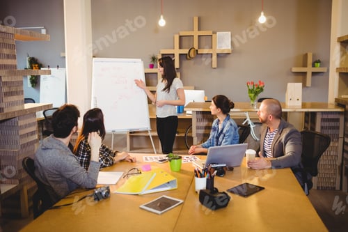 Preview: Female graphic designer discussing chart on white board with coworkers