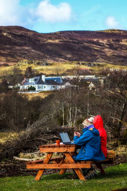 Preview: Vertical shot of people sitting and working on a picnic table in Isle of Skye, Scotland, UK