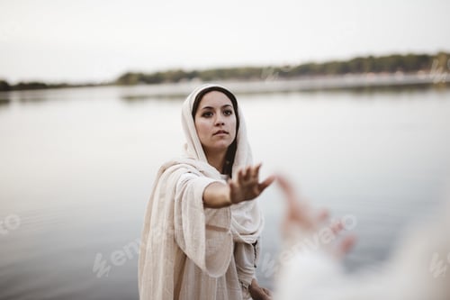 Preview: Shallow focus shot of a female wearing a biblical robe while reaching towards hand of Jesus Christ