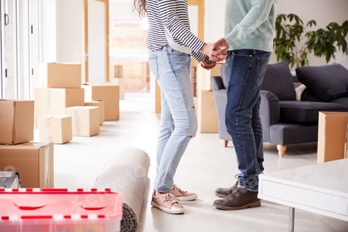 Preview: Close Up Of Loving Couple Holding Hands Surrounded By Boxes In New Home On Moving Day