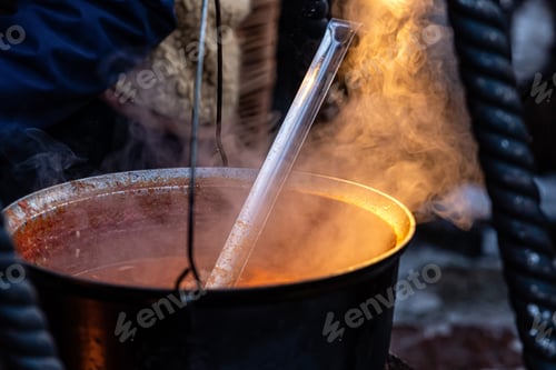 Preview: large metal soup pot on an open fire at an open-air Christmas market, street food, close-up