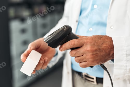Preview: Senior pharmacist scans medicine package at checkout counter