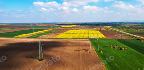Preview: Aerial shot of transmission towers electricity pylons with power lines in cultivated field