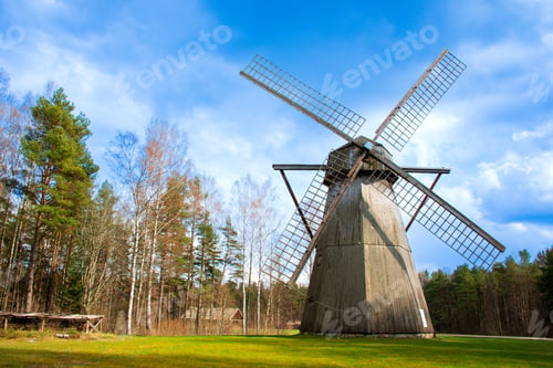 Preview: Traditional wooden windmill standing tall in a scenic countryside surrounded by pine trees