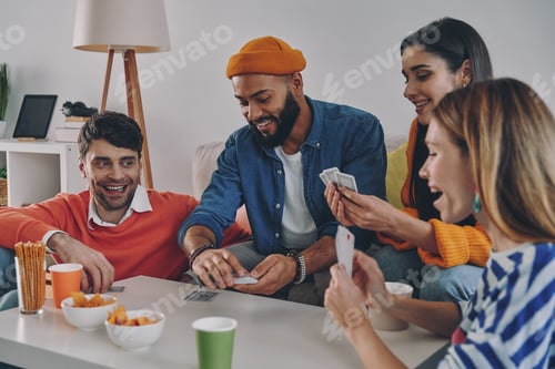 Preview: Cheerful young people playing cards while enjoying carefree time together