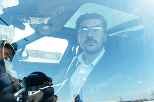 Preview: Young businessman in elegant suit driving luxury car