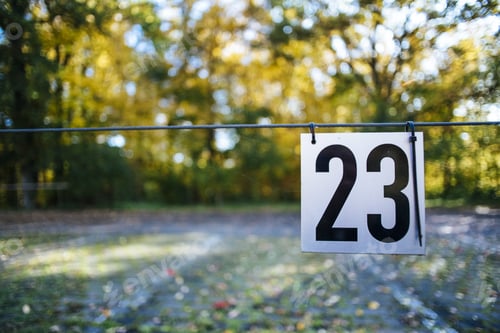 Preview: Selective focus of the number 23 sign hanging from a metallic wire in the park