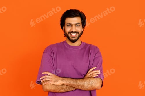 Preview: Handsome confident indian guy in casual posing on orange background