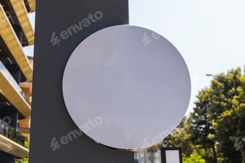 Preview: A blank circular sign is displayed on a grey wall of a contemporary building
