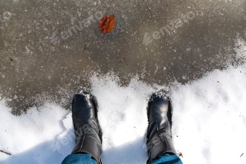 Preview: Feet in boots in a frozen puddle