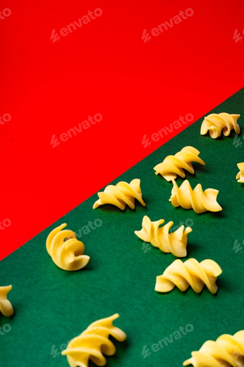 Preview: Diagonally arranged fusilli pasta on red and green background, concept italian cuisine