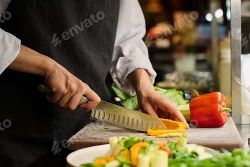 Preview: Close-up of hands of young female kitchen worker chopping fresh pepper