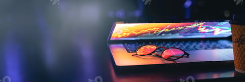 Preview: Glasses lie on the laptop, reflecting light from the screen in the dark.