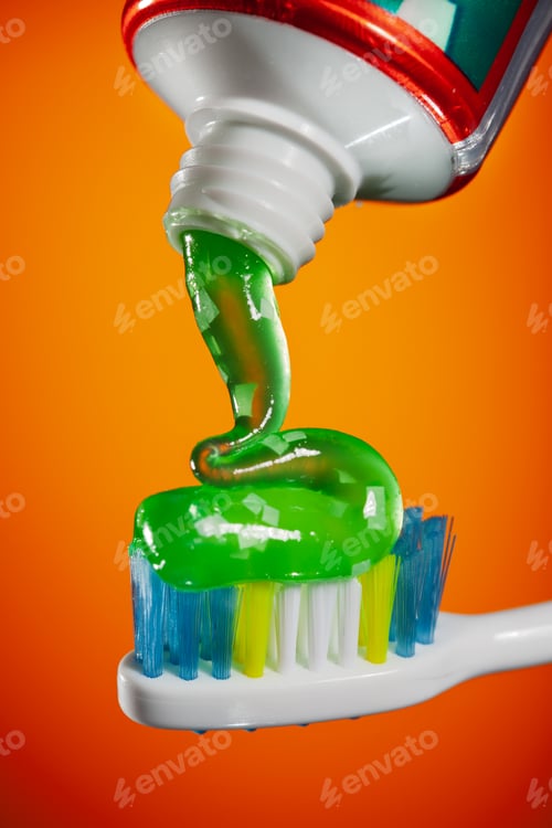 Preview: Closeup of fresh green gel toothpaste being squeezed from tube onto toothbrush
