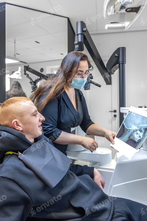 Preview: Young female dentist showing a patient a dental x-ray. Dentistry concept.