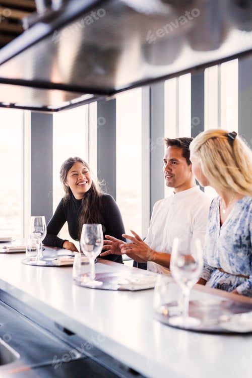 Preview: Young man with female friends having conversation in restaurant