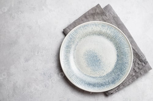 Preview: A ceramic blue plate with a linen napkin on a light textured background.