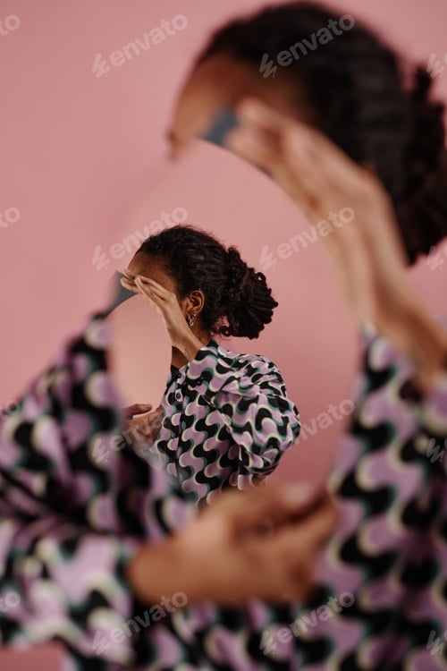 Preview: Unrecognizable black woman holding mirror with optical illusion