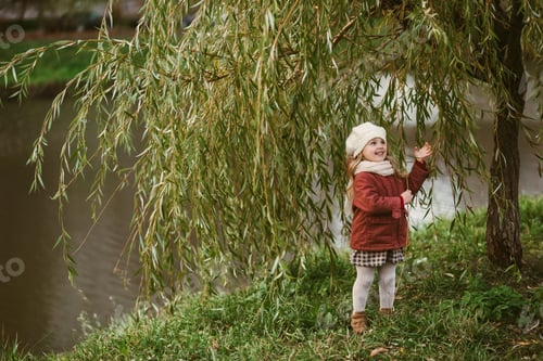 Preview: A cute girl is standing next to a willow tree