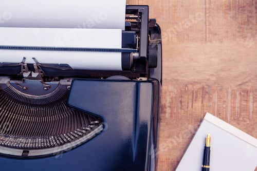 Preview: Pen and paper by typewriter on wooden table in creative office