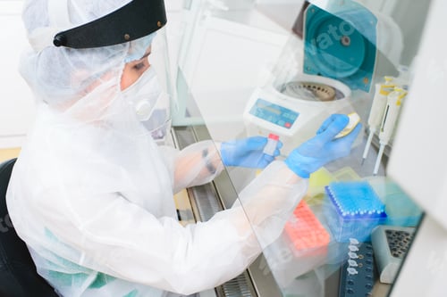 Preview: female PCR laboratory researcher in a protective medical suit, sterile mask, helmet, rubber gloves
