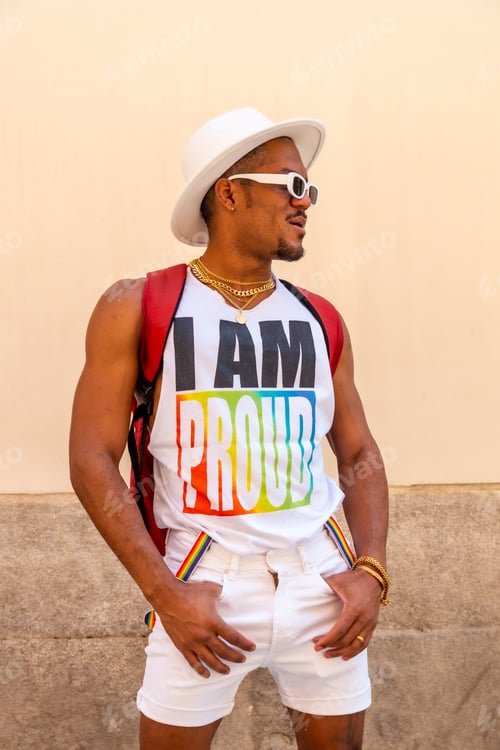 Preview: Portrait of a gay black ethnicity man at the pride party on a cream wall, LGBT flag, vertical photo