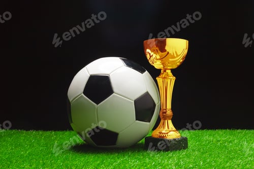 Preview: Soccer ball and golden trophy on green grass display during sports event celebration