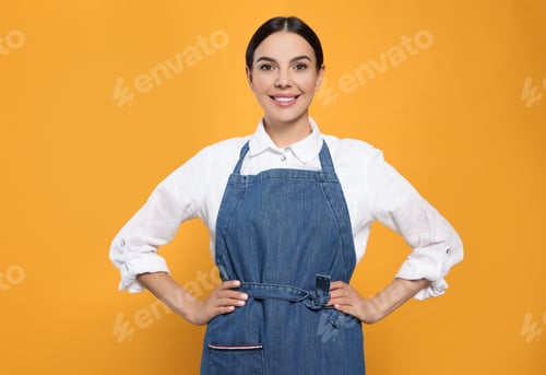 Preview: Young woman in blue jeans apron on yellow background