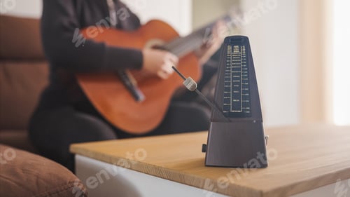 Preview: Musician practicing guitar using a metronome for perfect timing