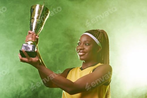 Preview: Smiling Female Athlete Holding Trophy with Green Smoke