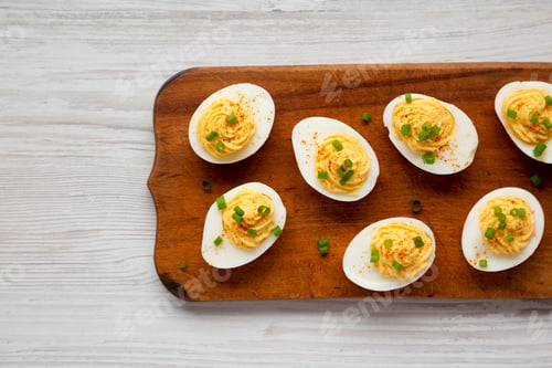 Preview: Homemade Deviled Eggs with Chives on a rustic wooden board, view from above.
