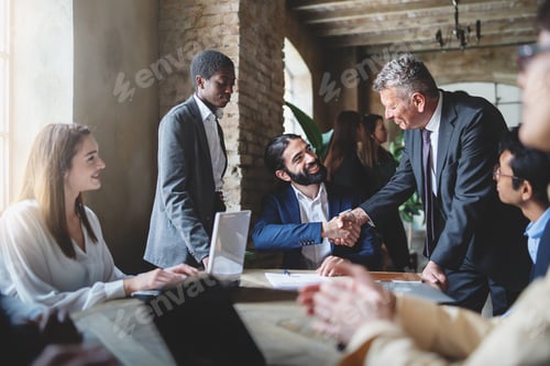 Preview: Two businessmen make a deal by shaking hands sitting at a table