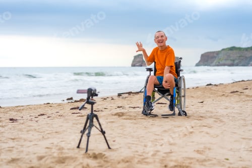 Preview: Portrait of a disabled person in a wheelchair on the beach recording a video blog