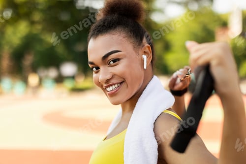 Preview: Smiling sporty black woman in yellow sportswear looking at camera