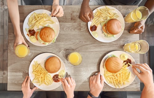 Preview: Plates of hamburgers, french fries, juice glasses on table