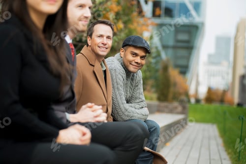 Preview: City life. A group of people on the go, keeping in contact, sitting on a bench. Men and women.