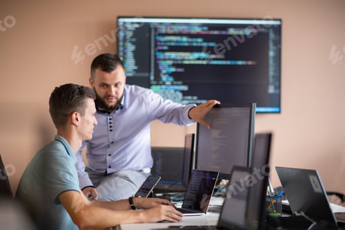 Preview: Programmers engrossed in deep collaboration, diligently working together to solve complex problems