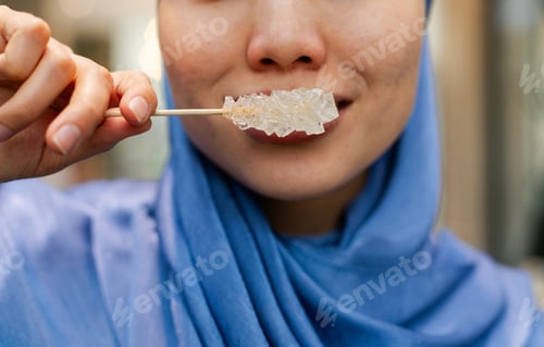 Preview: Closeup of woman holding stick of rock candies on a wooden stick