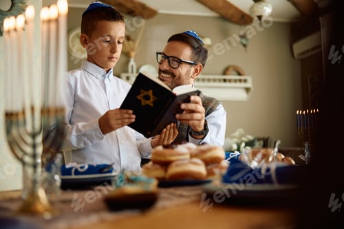 Preview: Happy father and son reading Hebrew bible during Hanukkah at home.