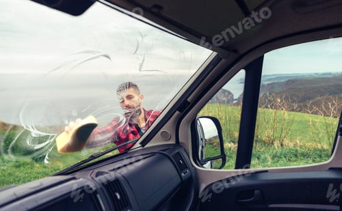 Preview: Man cleaning camper van windshield outdoor