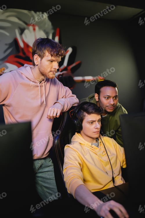 Preview: Focused multiethnic team playing video game on computer in gaming club