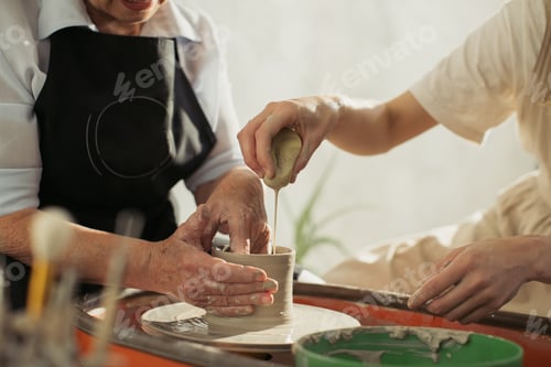 Preview: Senior woman learning pottery making with teacher assistance