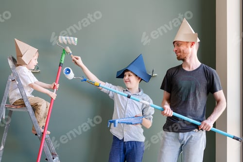 Preview: Happy boys and their dad start painting the wall. Happy boys renovating their new home.