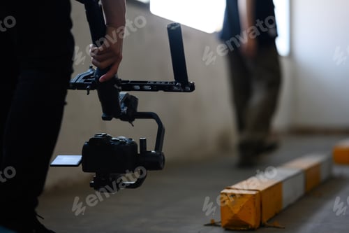 Preview: Videographer holding camera with stabilization gimbal shooting video of woman dancing.